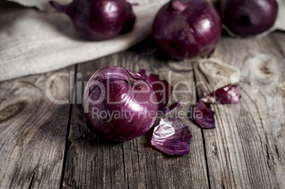Red onions in the husk on the gray old wooden surface