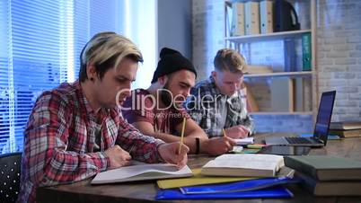 Several classmates taking lecure notes to notebook