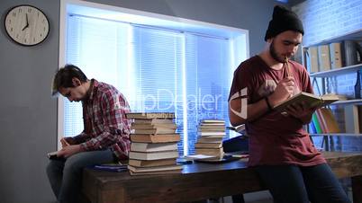 Male students doing research with books in library