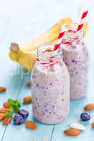 Banana and blueberry diet smoothie with yogurt or milk, almonds and fresh berries in glass bottles, healthy food