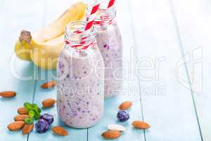 Banana and blueberry diet smoothie with yogurt or milk, almonds and fresh berries in glass bottles, healthy food