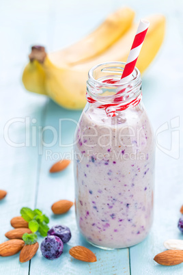 Banana and blueberry diet smoothie with yogurt or milk, almonds and fresh berries in glass bottles, healthy food