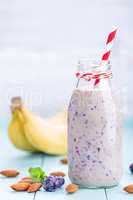 Banana and blueberry diet smoothie with yogurt or milk, almonds and fresh berries in glass bottles, healthy food