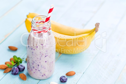 Banana and blueberry diet smoothie with yogurt or milk, almonds and fresh berries in glass bottles, healthy food