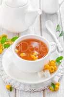 Fresh warmer herbal hawthorn tea with fresh berries in a white cup on wooden background, alternative medicine