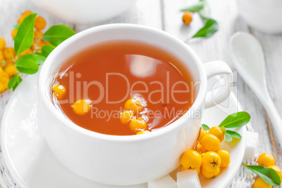 Fresh warmer herbal hawthorn tea with fresh berries in a white cup on wooden background, alternative medicine