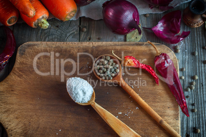 Salt and dried allspice in a wooden spoon on the kitchen blackbo