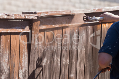 Professional Painter Spraying Yard Fence with Stain