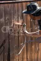 Professional Painter Spraying Yard Fence with Stain