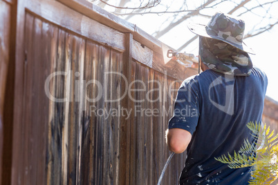 Professional Painter Spraying Yard Fence with Stain