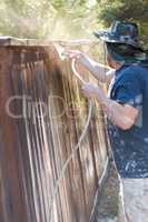 Professional Painter Spraying Yard Fence with Stain