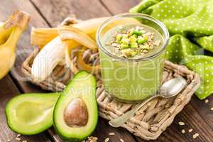 Avocado and banana smoothie with oats with ingredients in glass jar on wooden background, healthy eating