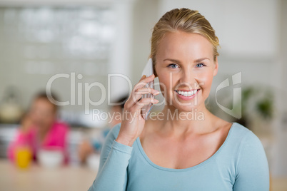 Smiling woman talking on mobile phone in kitchen