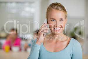 Smiling woman talking on mobile phone in kitchen