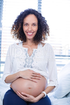 Portrait of pregnant woman relaxing on hospital bed in ward