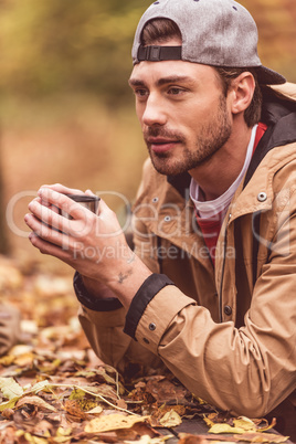 Young man holding cup from thermos
