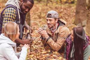 Friends pouring hot drink in forest