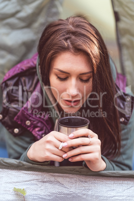 Woman in tent holding metallic cup