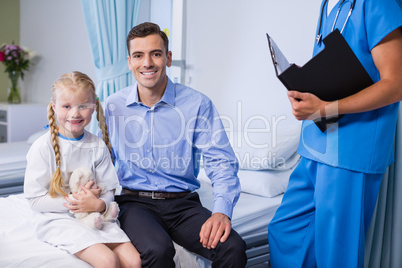 Portrait of sick girl and father in hospital bed