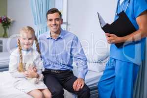 Portrait of sick girl and father in hospital bed