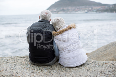 Senior couple sitting on rock at beach