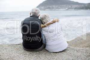 Senior couple sitting on rock at beach