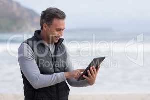 Mature man using digital table on the beach