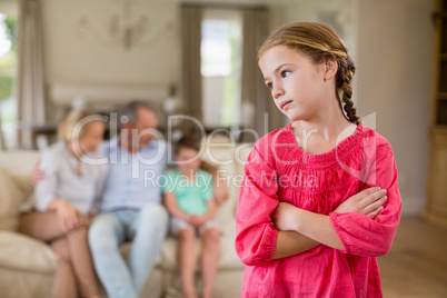 Thoughtful girl standing with arm crossed in living room