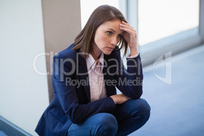 Worried businesswoman crouching on floor