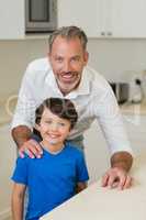 Portrait of father and son standing in kitchen