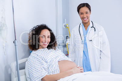 Portrait of doctor examining pregnant woman in ward
