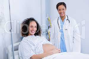Portrait of doctor examining pregnant woman in ward