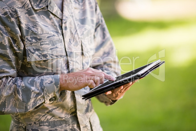 Mid-section of soldier using digital tablet in park