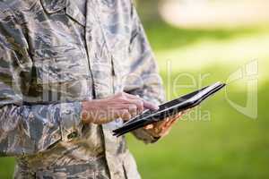 Mid-section of soldier using digital tablet in park