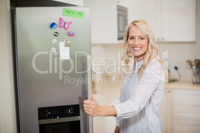 Beautiful woman opening refrigerator door in kitchen