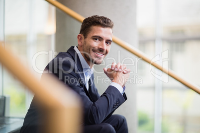Happy businessman sitting on steps