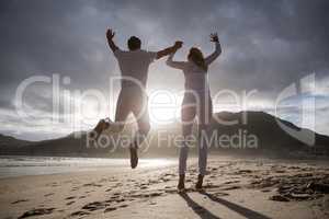 Mature couple jumping in air on the beach
