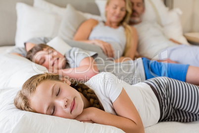 Parents and kids sleeping on bed in bedroom