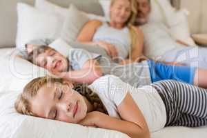 Parents and kids sleeping on bed in bedroom