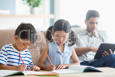 Attentive siblings doing homework in living room