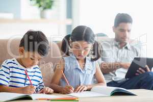 Attentive siblings doing homework in living room