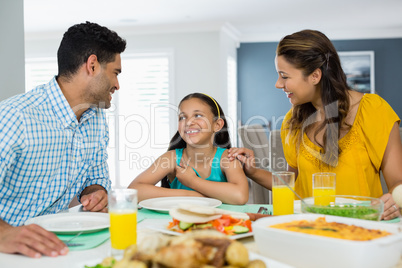 Daughter and parents having meal on table at home