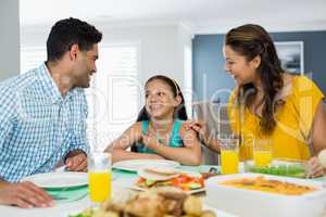 Daughter and parents having meal on table at home