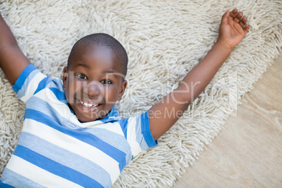 Portrait of boy lying on rug in living room