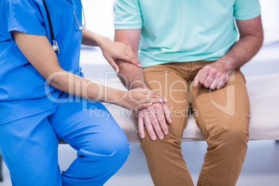 Mid section of doctor consoling senior patient