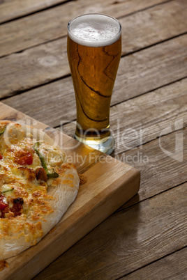 Delicious pizza served on wooden board with a glass of beer