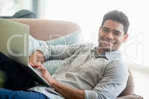 Man sitting on sofa and using laptop in living room at home