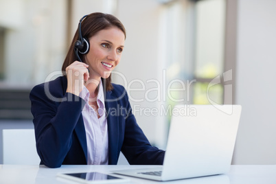 Businesswoman wearing headphone using laptop