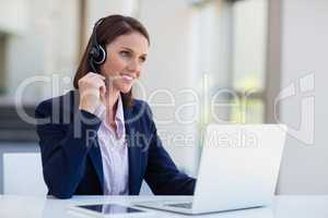 Businesswoman wearing headphone using laptop