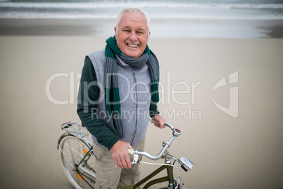 Portrait of senior man riding bicycle on the beach